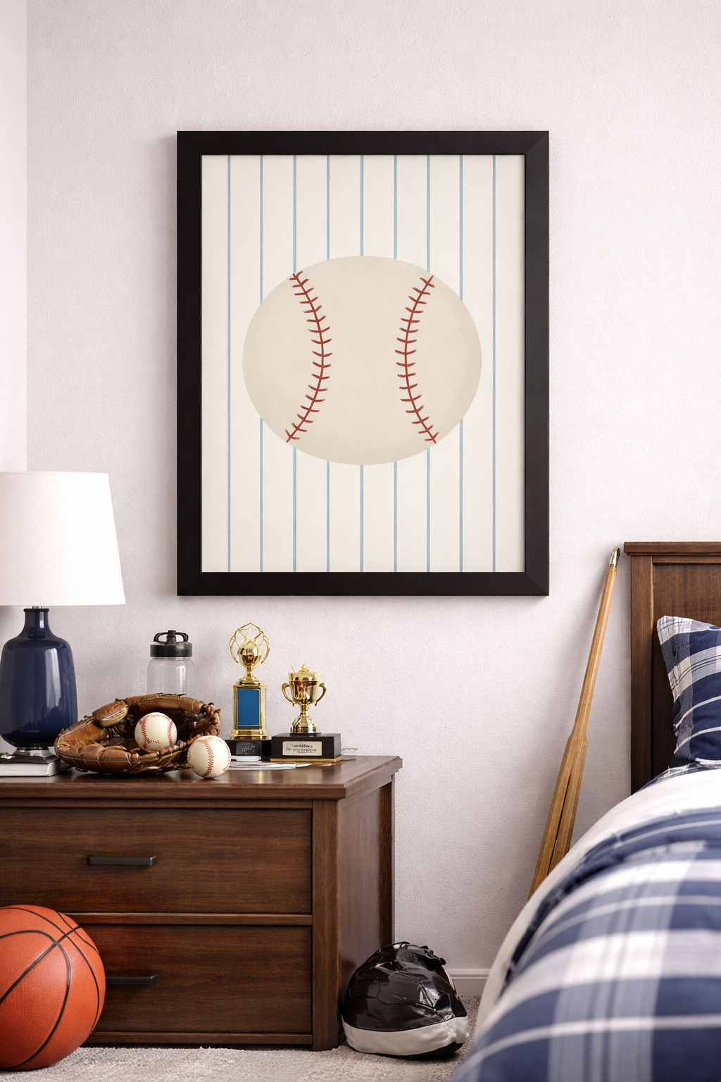 Framed baseball wall art featuring a classic baseball on a striped background for sports bedroom or baseball themed nursery decor. Framed In Black hanging on a wall in a kid's room.