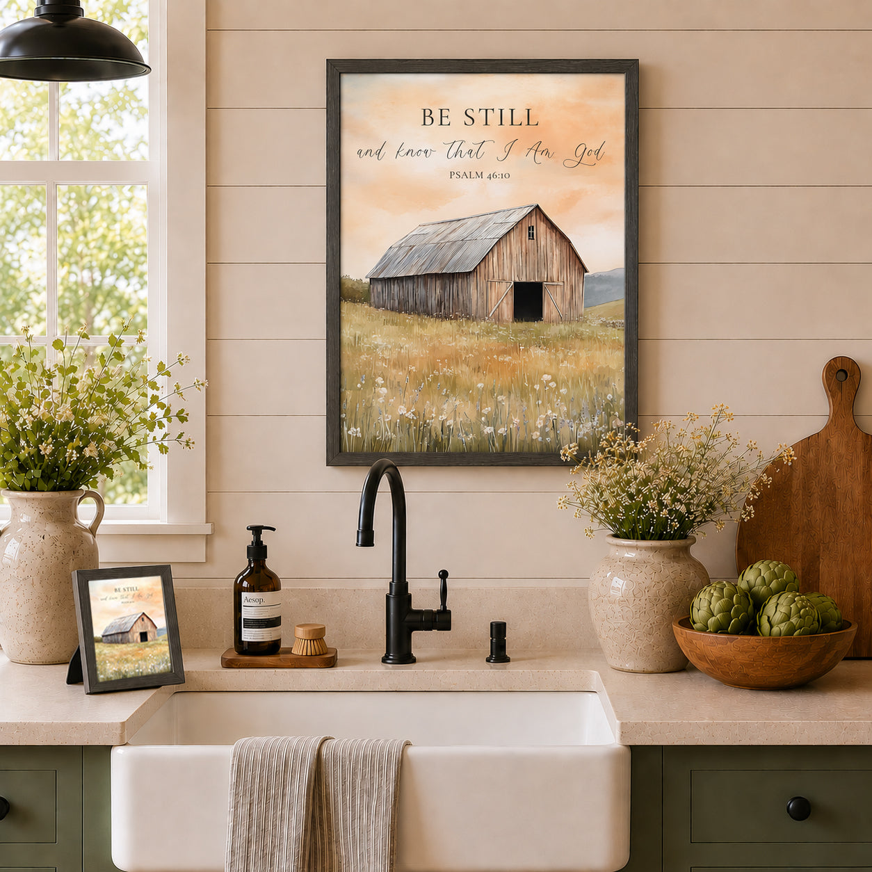 Farmhouse kitchen with Be Still and Know That I Am God Psalm 46:10 wall art SB255 in slatewood frame above white farmhouse sink on shiplap — larger size on wall and 8x10 easel back on counter beside Aesop soap and cutting board