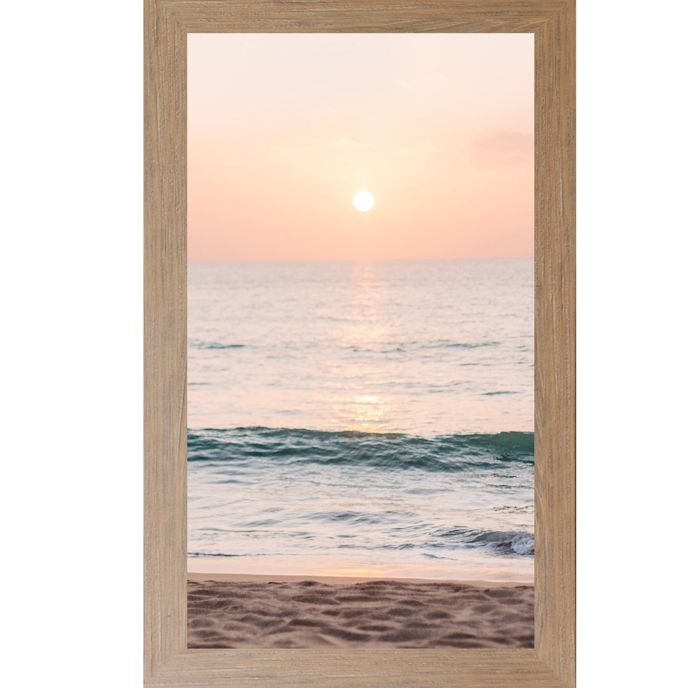 Farmtable framed tall portrait beach sunset wall art featuring a glowing sun above the horizon with soft peach and coral sky, shimmering teal ocean waves, and sandy shoreline