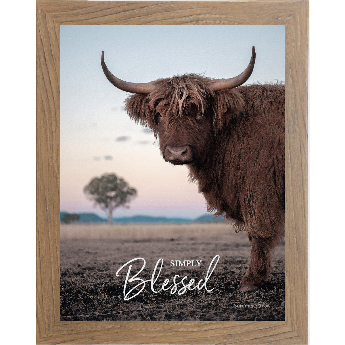 Farmtable framed vertical farmhouse portrait wall art featuring a Highland cow with curved horns standing in a twilight field with a soft blush sky and lone tree with the words Simply Blessed