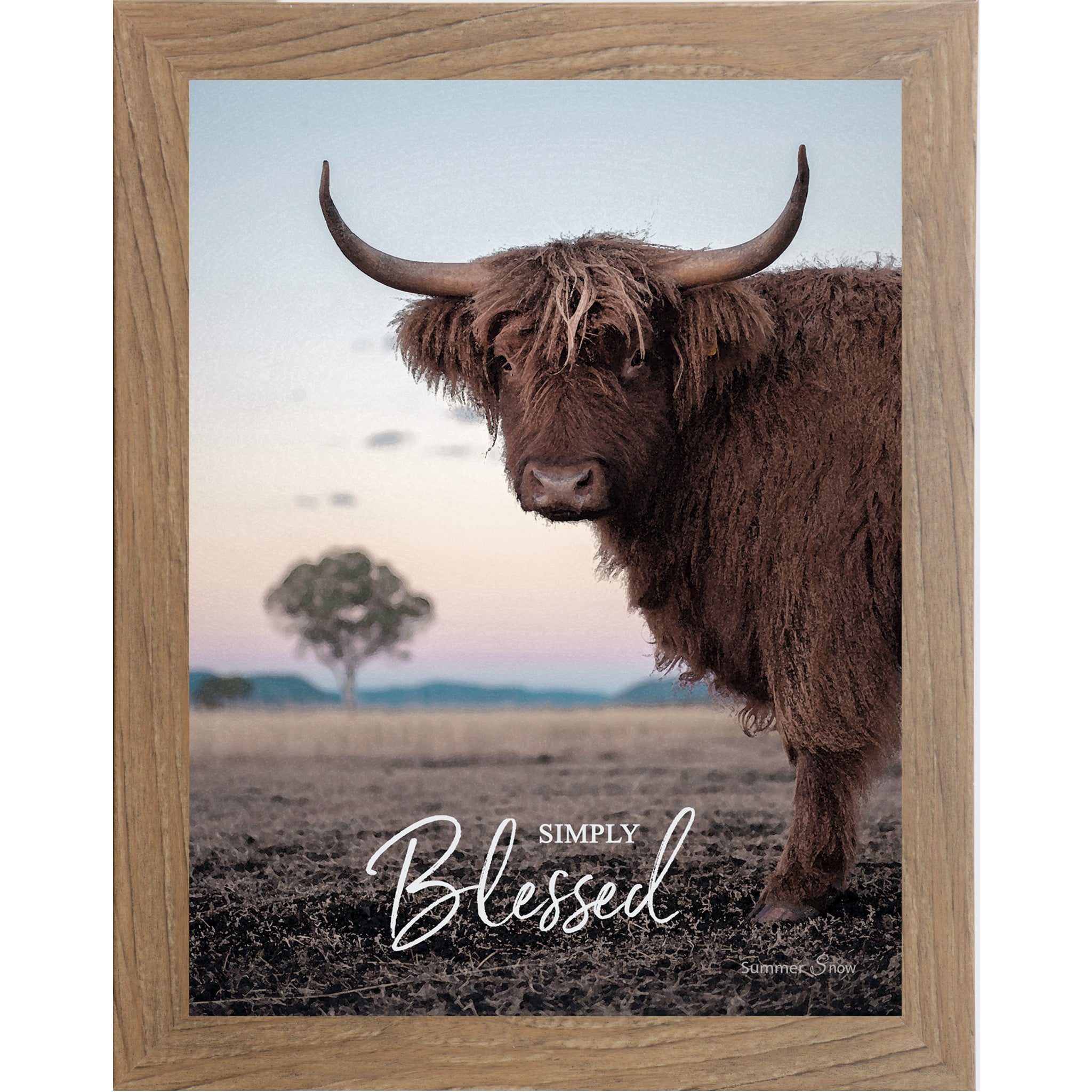 Farmtable framed vertical farmhouse portrait wall art featuring a Highland cow with curved horns standing in a twilight field with a soft blush sky and lone tree with the words Simply Blessed