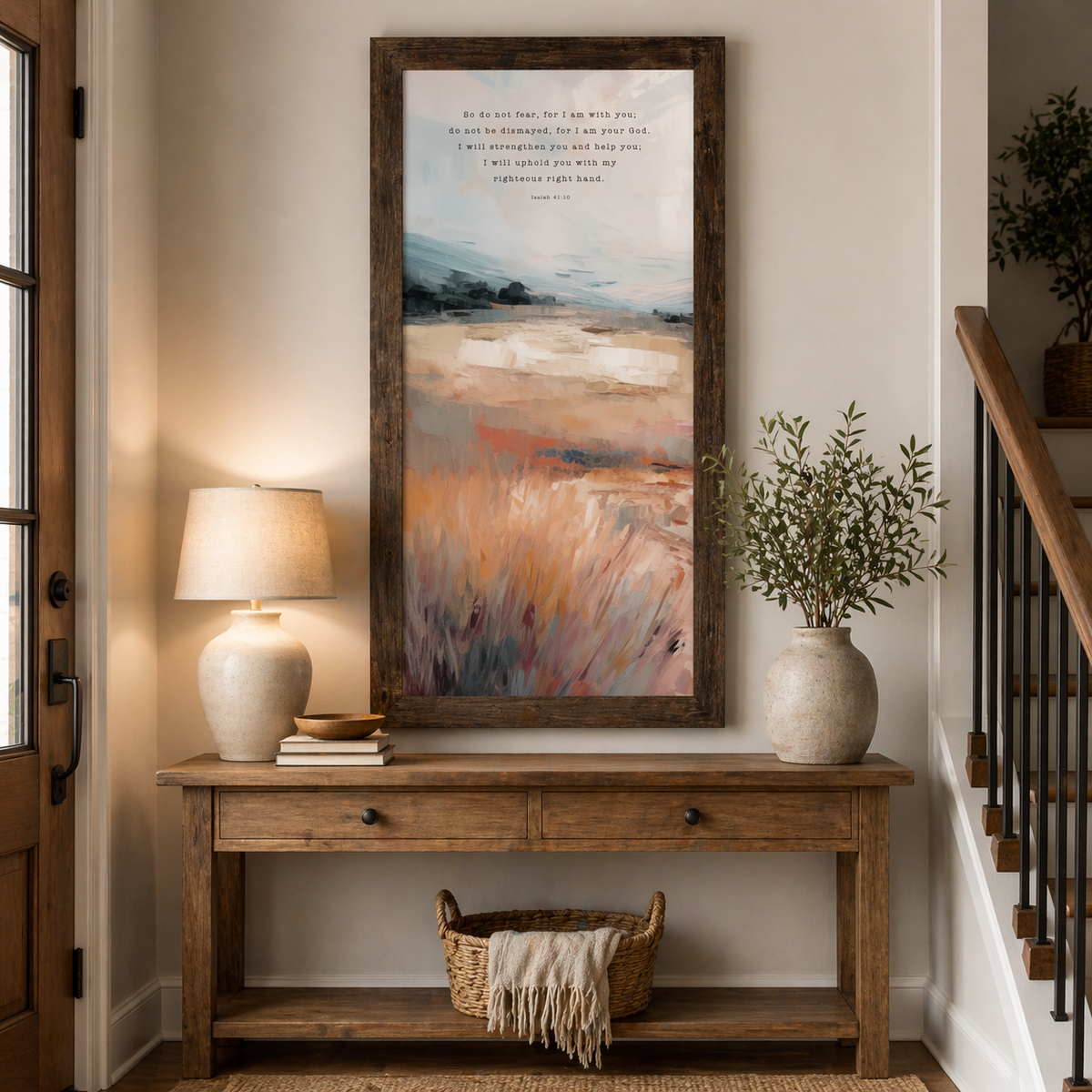 Natural Brown framed tall portrait Christian wall art displayed at large scale in a warm farmhouse entryway with wooden console table beside staircase showing Isaiah 41:10 do not fear for I am with you scripture in typewriter typography over warm orange terracotta painterly landscape with blue-grey sky