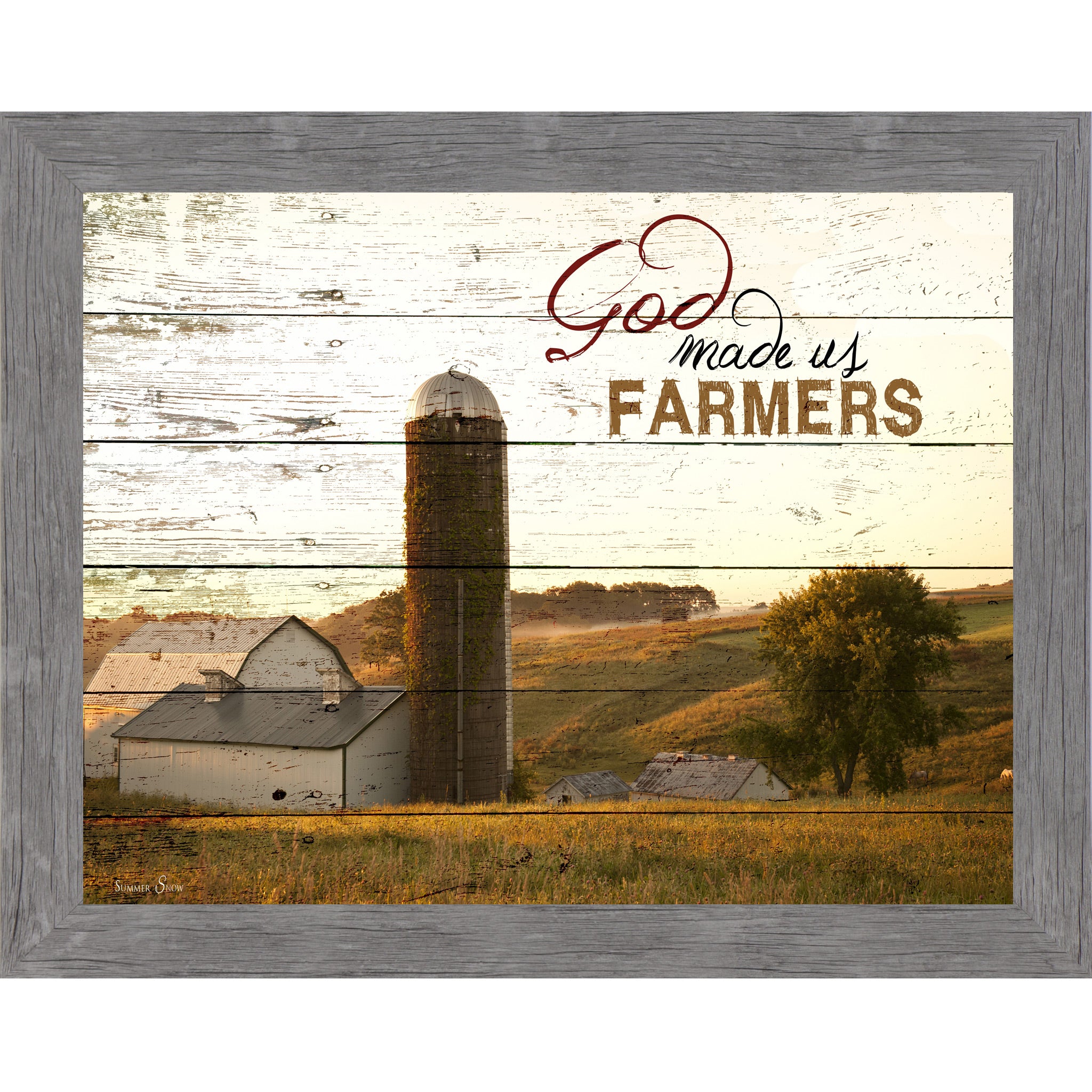 Gray framed horizontal farmhouse landscape wall art featuring a white barn and silo on rolling green hills with pallet wood background and the words God Made Us Farmers
