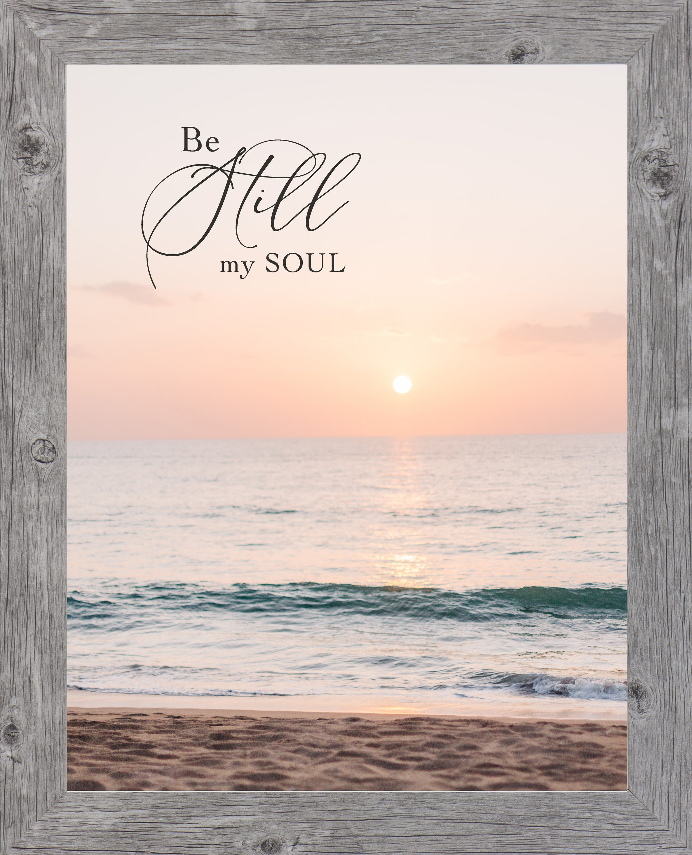 Gray framed portrait Christian wall art with the words Be Still My Soul in elegant script set against a soft peach and coral beach sunset with teal ocean waves and sandy shoreline