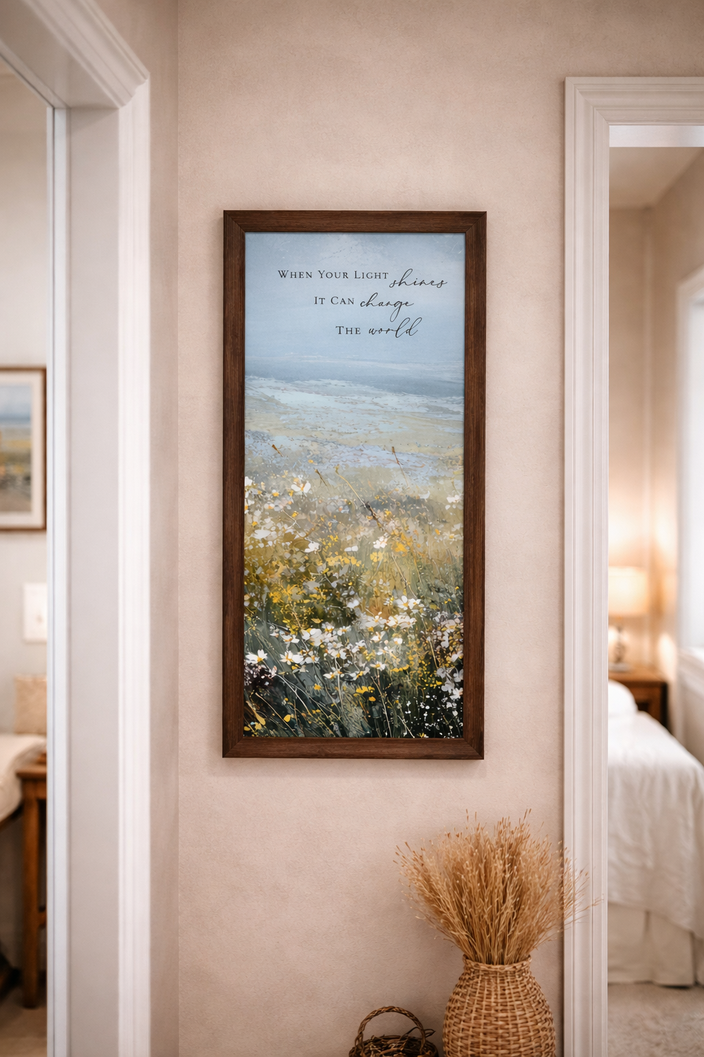 Natural Brown color Framed inspirational wall art featuring a watercolor meadow of wildflowers in bloom with rolling fields and a soft blue sky. The artwork includes the quote “When Your Light Shines It Can Change The World.” Set in a hallway