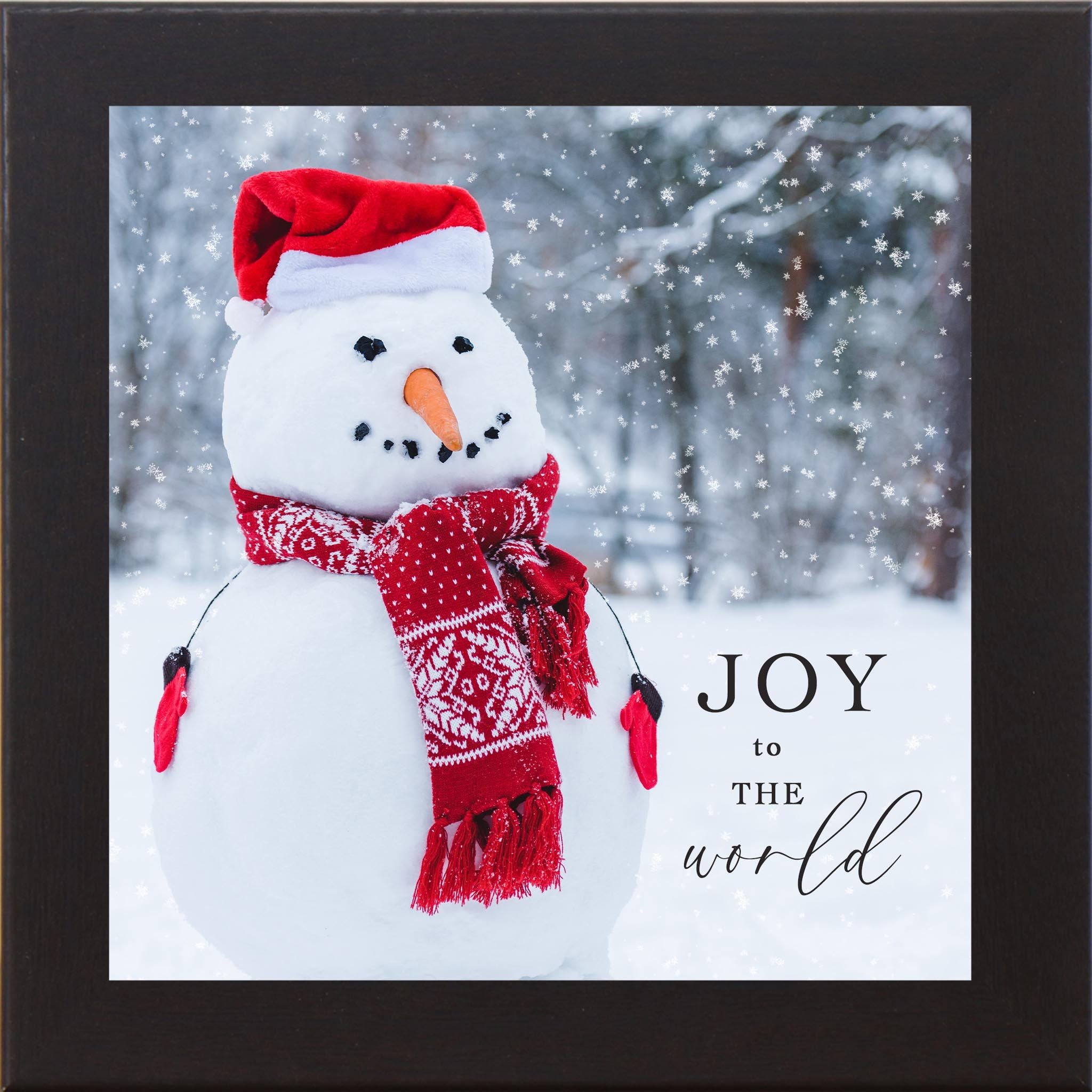 Joy To The World SN48 winter snowman wall art featuring a short snowman wearing a red scarf, Santa hat, and red mittens, with a carrot nose and coal eyes, standing in falling snow beside a softly blurred forest background.