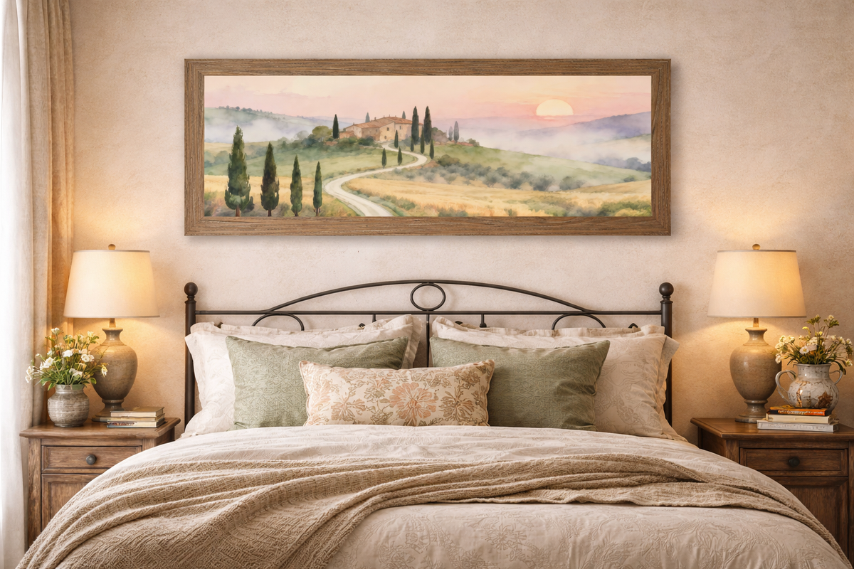 Farmtable framed 40x14 wide landscape Tuscan sunrise road watercolor wall art displayed above a bed in a Tuscany themed bedroom with warm neutral linens soft lighting and Italian countryside decor