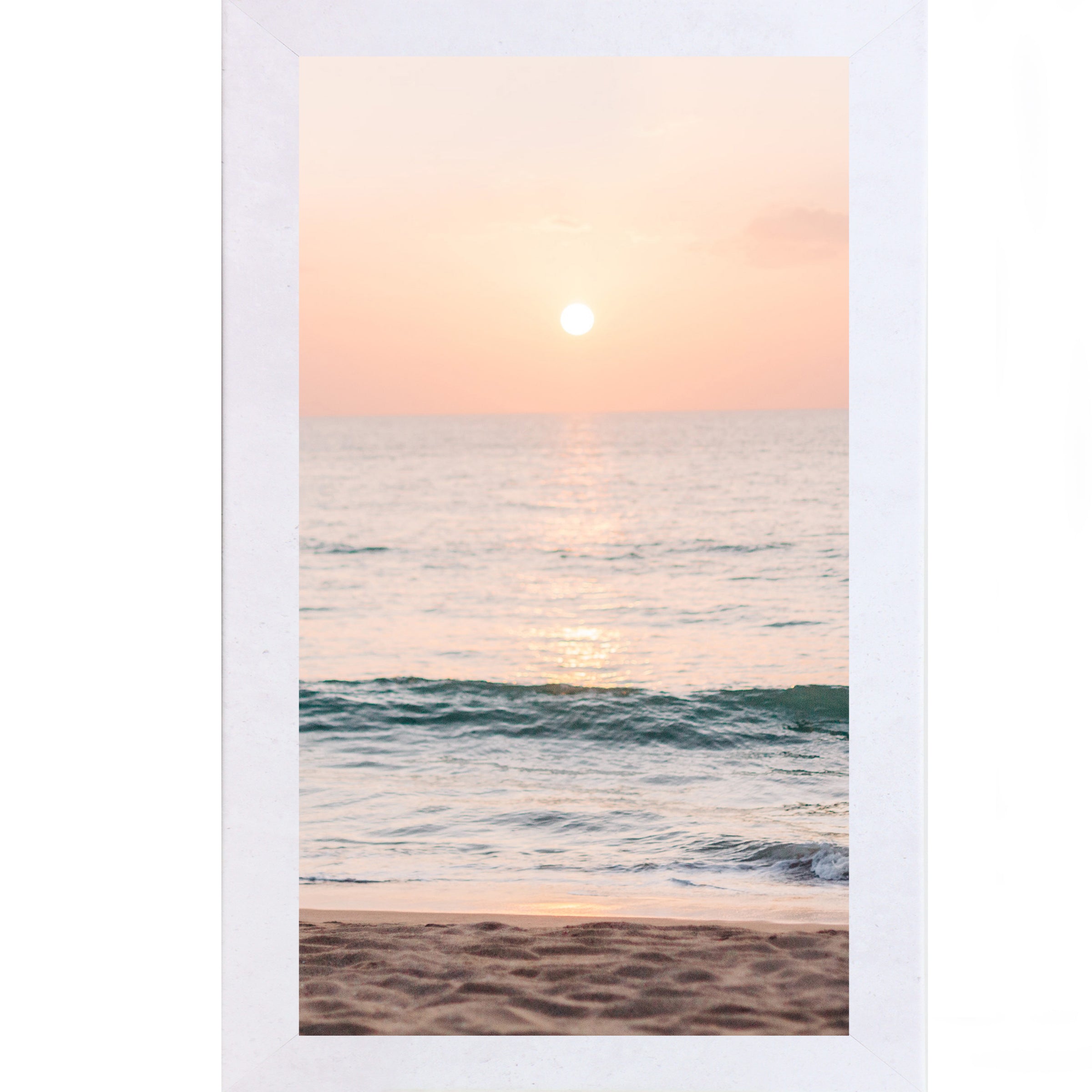 Terracotta white framed tall portrait beach sunset wall art featuring a glowing sun above the horizon with soft peach and coral sky, shimmering teal ocean waves, and sandy shoreline