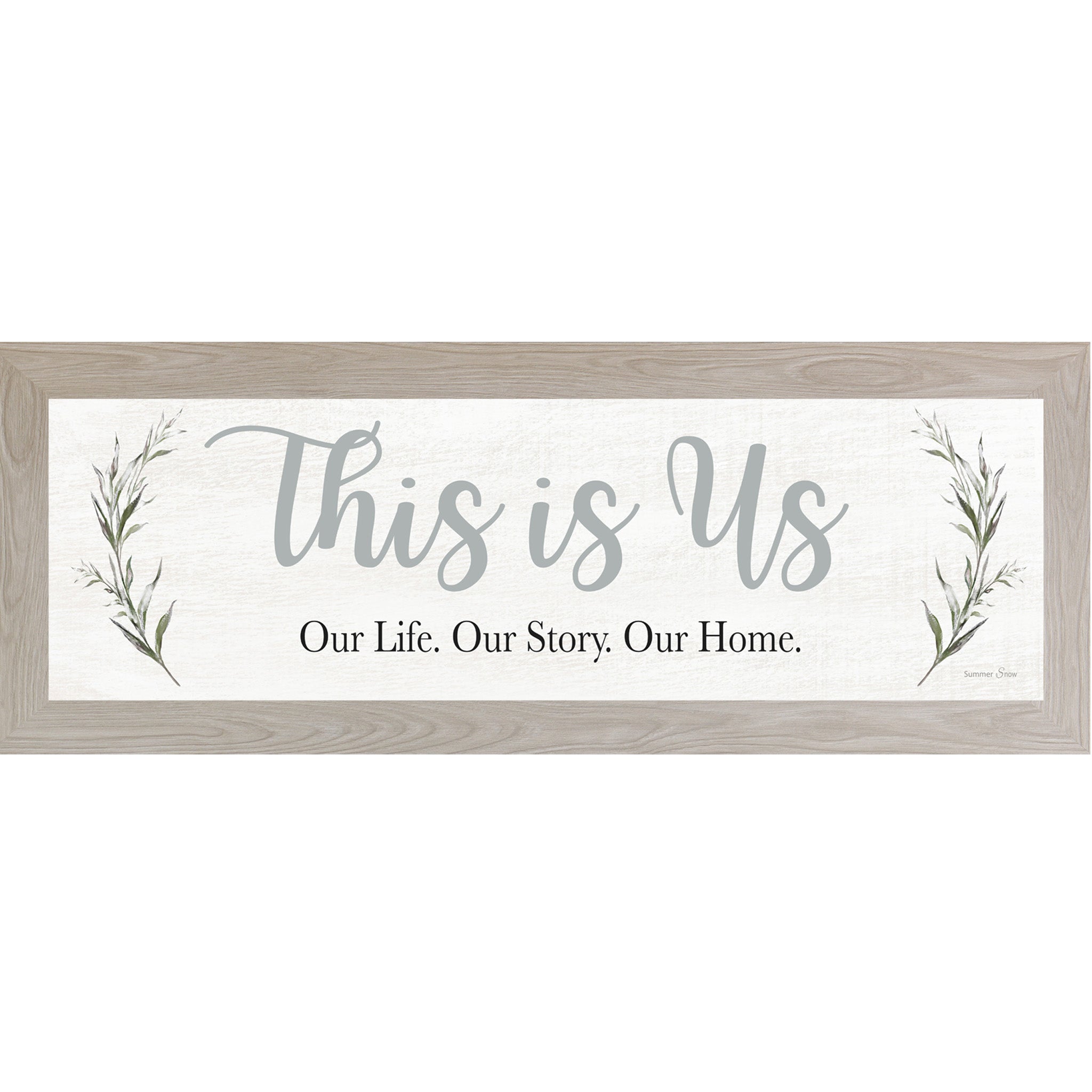 Framed family wall art with the quote This Is Us Our Life Our Story Our Home on a near-white background with soft floral leaves on each side